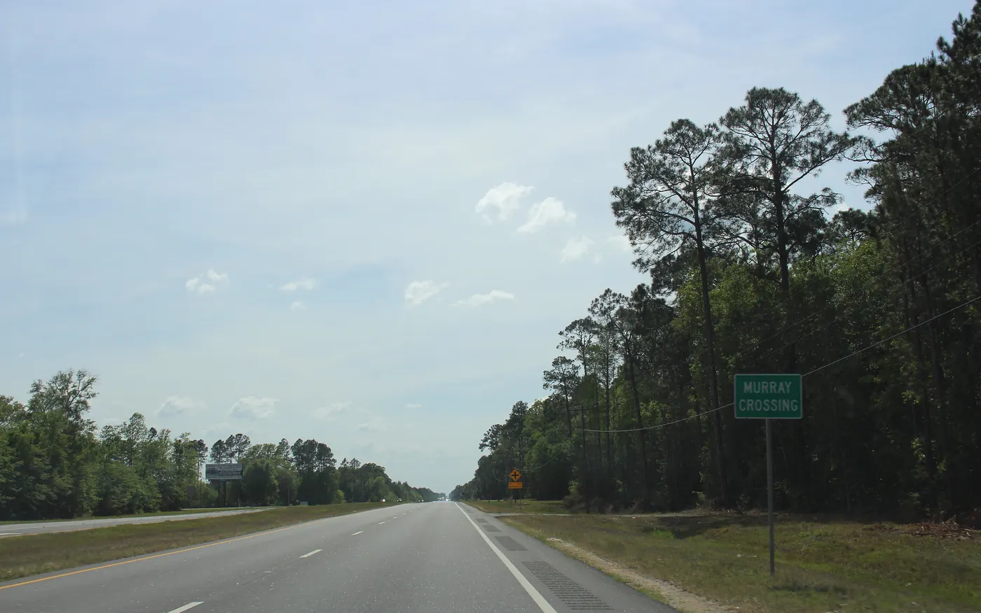 Open rural stretch of US-84 between pine stands at Murray Crossing in Long County, Georgia